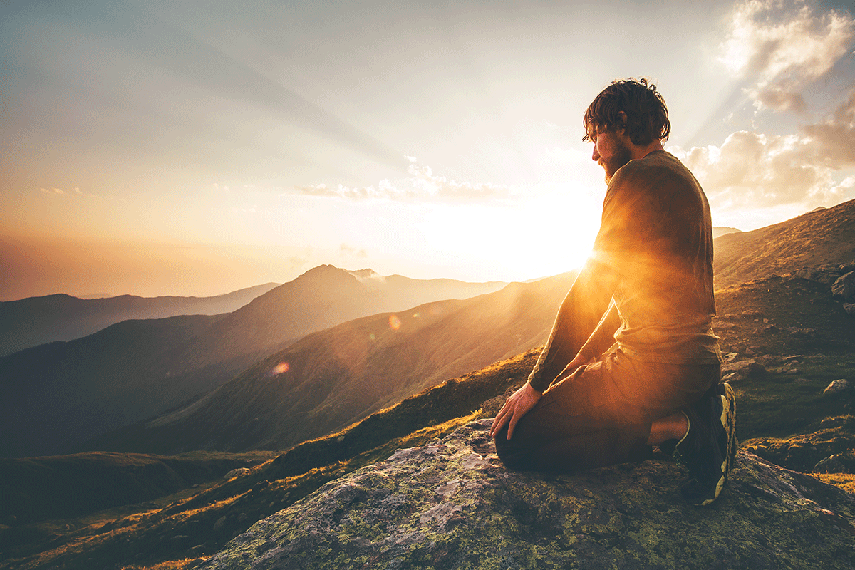 Man sitting on edge of of mountain, after achieving unity of mind, body, and soul